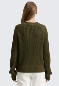 Gruby, oliwkowy sweter z dzianiny o prążkowanej strukturze, okrągłym dekoltem i długimi rękawami. Charakteryzuje się luźnym krojem z opadłymi szwami na ramionach.