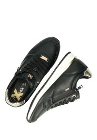 Černé kožené tenisky s bílou podrážkou, zlatými kovovými detaily a zipem na boku. Zahrnují černé šňůrky a strukturovaný lem.