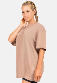 Oversized beige t-shirt van zacht katoen, met een ronde hals, korte mouwen en subtiele logo borduursel op de borst.