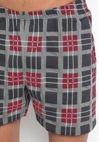 Boxer in grigio con motivo a quadri, caratterizzati da dettagli in rosso, nero e bianco. Vita elastica e tessuto morbido e texture.