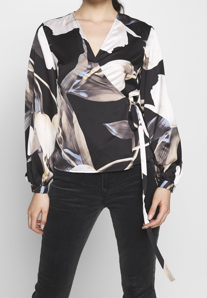 Zwarte wikkelblouse met een bloemenpatroon in beige, grijs en wit. Lange mouwen met elastische manchetten en een strikdetail in de taille. Gladde stof.