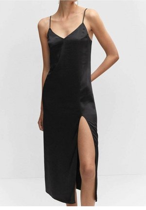 Robe en satin noire avec fines bretelles et une fente haute à la cuisse côté gauche, portée par une personne ayant une main dans le dos.