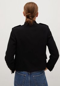 Czarna krótka kurtka z pagonami na ramionach i mankietami na guziki, wykonana z gładkiej tkaniny. Charakteryzuje się gładkim tyłem i dopasowanym krojem.