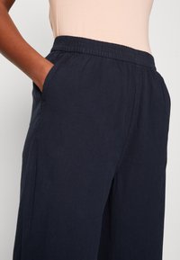 Námořnické široké kalhoty s elastickým pasem a bočními kapsami, vyrobené z měkké a lehké tkaniny, s hladkým povrchem.