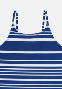 Navyblå og hvite stripete tanktopp med tynne stropper. Laget av et glatt, elastisk stoff med horisontale striper i varierende bredder.