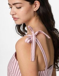 Abito a fascia a righe rosa e bianche con spalline annodate, schiena scoperta e una morbida texture di tessuto leggero.