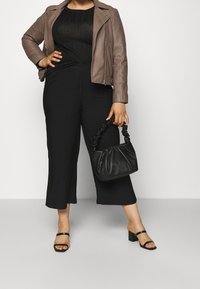 Brun läderbikerjacka, svart ribbad topp, svarta cropped byxor, svarta blockklackade sandaler och en liten svart veckad handväska.