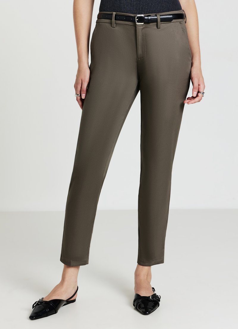 Pantaloni su misura verde oliva con una texture liscia, taglio dritto e cintura nera. Abbinati a ballerine nere con punta a punta.