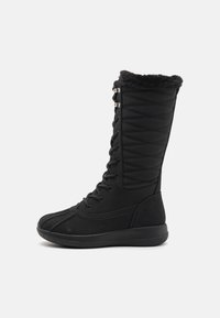 Botas negras hasta la rodilla con un diseño acolchado, cuello de piel sintética, cierre con cordones en la parte delantera y suela de goma para mayor tracción. Materiales lisos y texturizados.