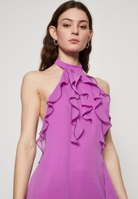 Robe halter violette avec un col froncé et un design fluide. Tissu léger avec une texture lisse et des lignes épurées.