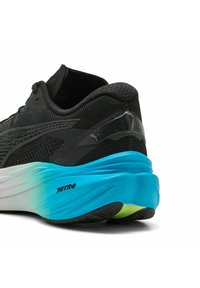 Scarpa da corsa nera con tomaia in rete, accenti riflettenti e suola testurizzata che transita dal blu al verde nella zona del tallone. Branding "NITRO" visibile.