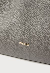 Geantă din piele gri, cu un finisaj texturat și un logo auriu "FURLA". Forma este dreptunghiulară, cu colțuri rotunjite.
