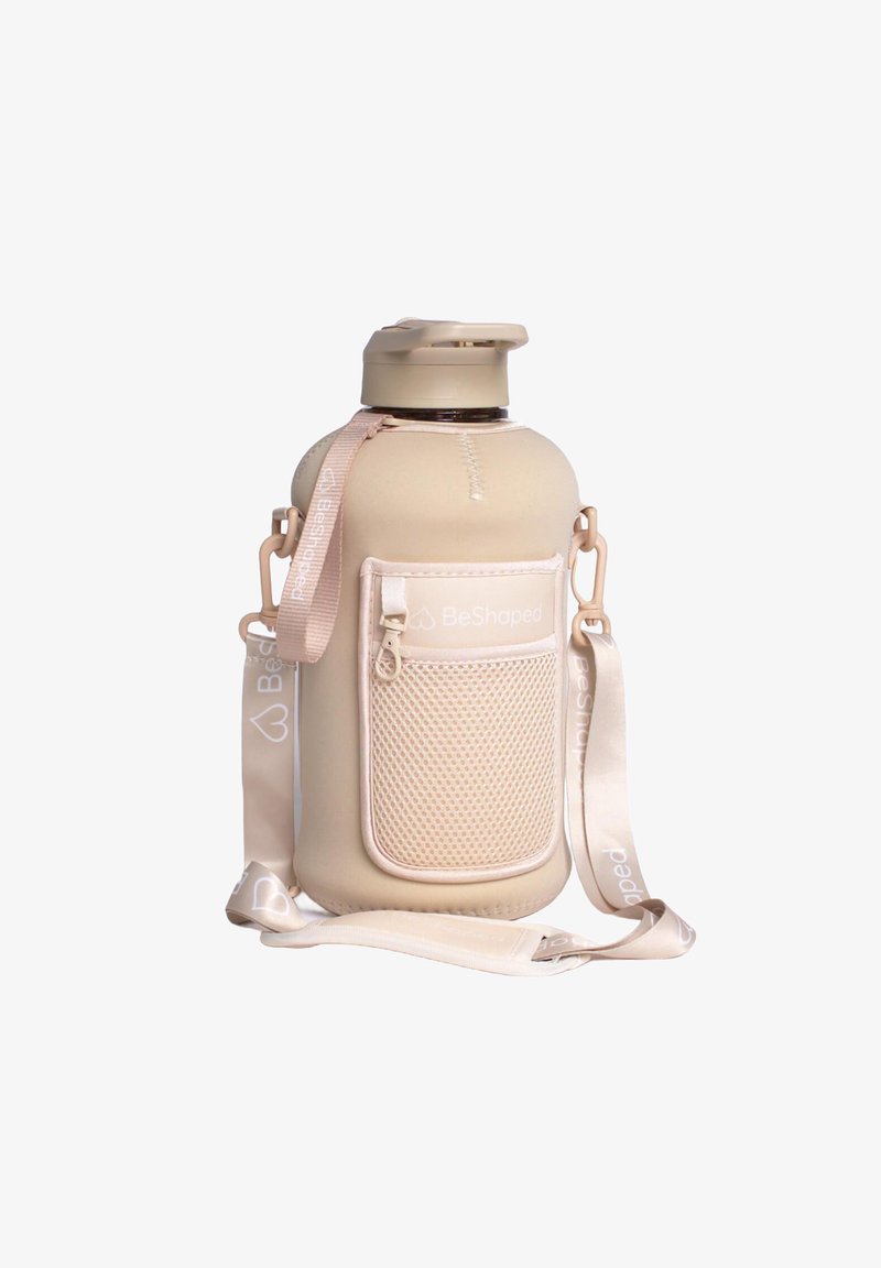 Butelka BeShaped z miękkim beżowym silikonowym pokrowcem, teksturowaną siateczką i paskiem do noszenia. Posiada klapkę z tworzywa.