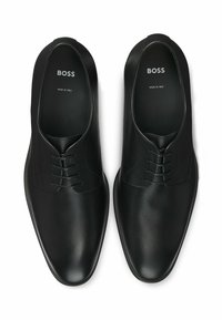 Black leather dress shoes featuring a smooth texture, rounded toe, and five-lace design. "BOSS" and "MADE IN ITALY" labels inside.
