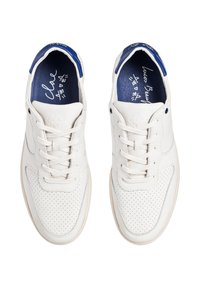 Sneakers bianchi in pelle con un design perforato, dettagli blu sul tallone e suole in gomma beige. Le stringhe sono bianche con una texture liscia.