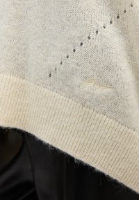 Maglione a maglia beige chiaro con orlo a costine, caratterizzato da un motivo testurizzato e un logo sottile sul lato inferiore destro.