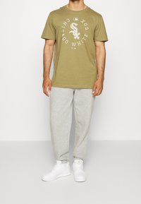 Olivově zelené bavlněné tričko s bílým logem Chicago White Sox, doplněné světle šedými tepláky a bílými teniskami. Jednoduchý design, volný střih.