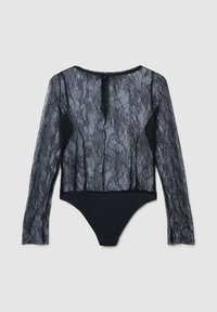 Body a maniche lunghe con parte superiore in pizzo nero trasparente con motivi floreali e parte inferiore nera opaca, con chiusura a zip sul retro.
