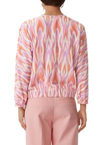Langarm blouse in een roze, oranje en lavendel ikatpatroon. Heeft een elastische zoom en manchetten met een soepele, lichte textuur.