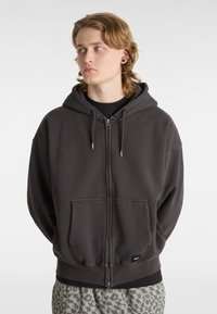 Graue Zip-Hoodie aus einem Baumwollmischgewebe. Verfügt über eine große Fronttasche, eine Kapuze mit Kordelzug und gerippte Bündchen. Lässige, lockere Passform.