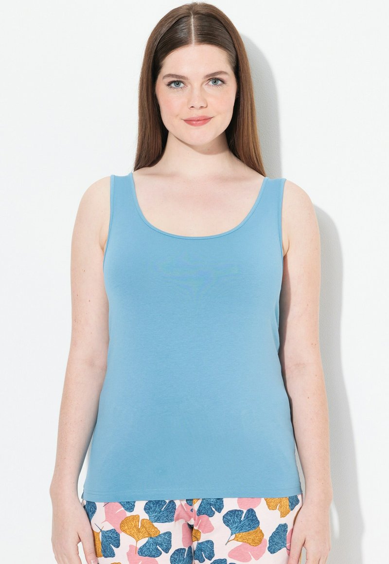 Débardeur bleu clair en tissu doux, doté d'un col rond et de larges bretelles, associé à un pantalon rose à motifs.