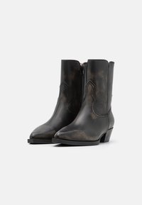 Bottes noires en cuir à la cheville avec un bout pointu et de la broderie décorative, dotées d'une fermeture éclair latérale et d'un petit talon empilé.