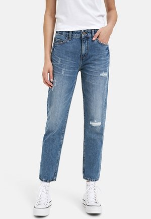 Light blue distressed denim jeans with a straight leg fit, five pockets, and a classic button fly, paired with white high-top sneakers.