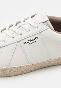 Hvide lædersneakers med flade snørebånd, tekstureret off-white sål og subtil branding. Features syede detaljer og en glat finish.
