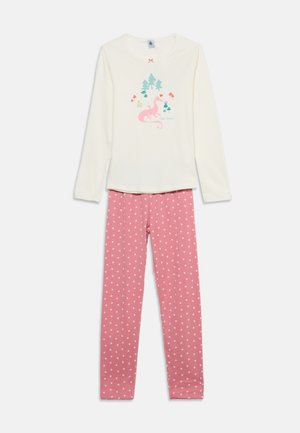 Haut crème à manches longues avec imprimé de dragon rose et d’arbres, associé à un legging rose avec petits motifs de cœurs blancs.
