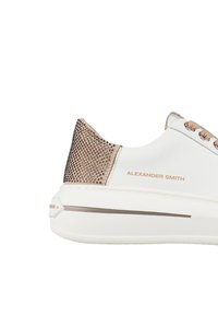 Sneaker bianca con borchie metalliche in rosa dorato sul tallone, lacci rosa dorato abbinati e "ALEXANDER SMITH" stampato di lato.