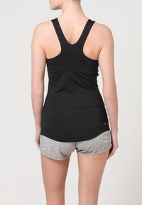 Černé tílko bez rukávů s přiléhavým střihem, doplněné šedými sportovními šortkami. Obě části jsou vyrobeny z měkkých, elastických materiálů.