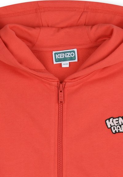 Sweat à capuche zippé rouge pour enfants avec étiquette "KENZO Kids" à l'intérieur du col et logo partiel "KENZO PARIS" sur la poitrine.