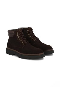 Botas de tobillo de ante marrón con cordones y ojales dorados. Presentan un detalle de cuero marrón en el cuello y una suela de goma negra resistente.
