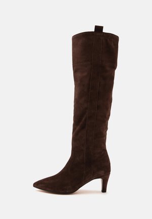 Botte haute en daim marron foncé avec bout pointu et talon de hauteur moyenne, présentée de profil sur fond blanc uni.