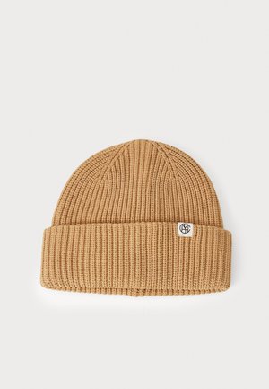 Knit beanie in beige with ribbed texture, foldable cuff, and a small logo tag. Made from soft material, suitable for cold weather.