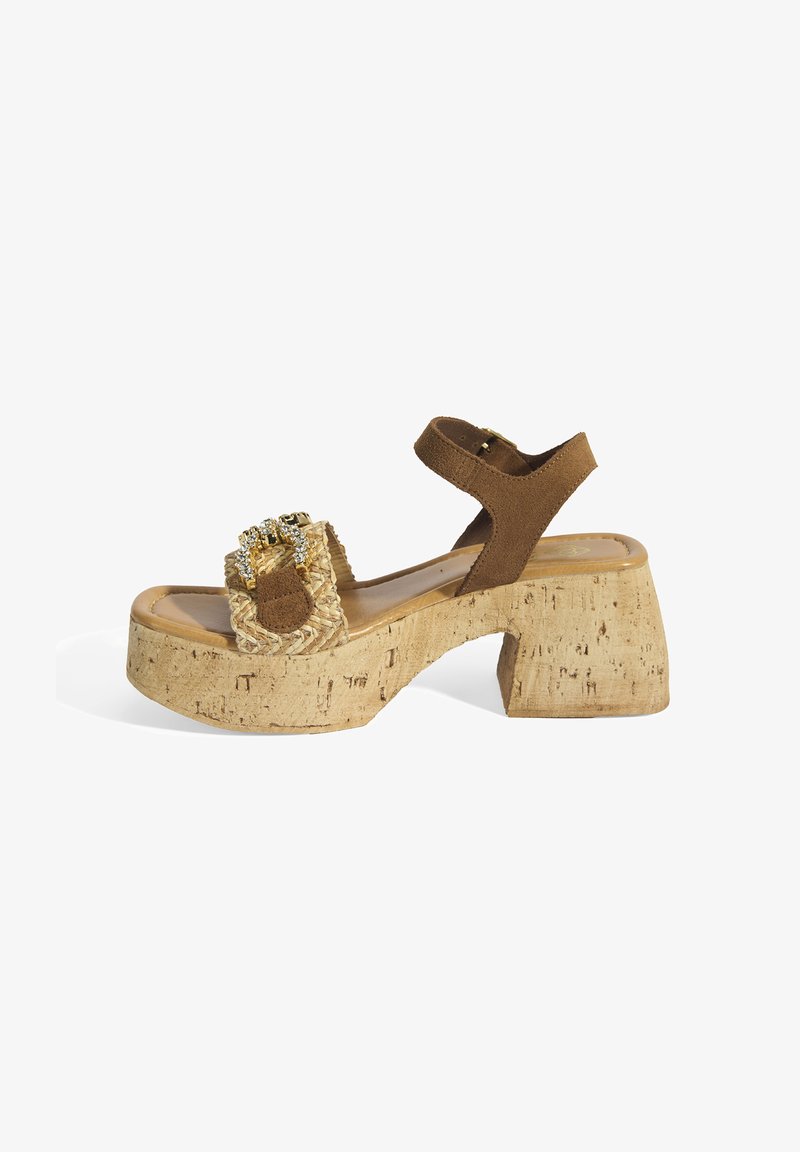 Brown suede platform sandals with cork heel, featuring woven straw detail and decorative hardware on the front strap. Adjustable ankle strap.