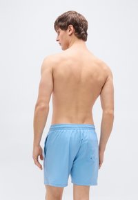 Ανοιχτό μπλε μαγιό με ελαστική μέση, πλαϊνές τσέπες και πίσω τσέπη. Κατασκευασμένο από υλικό που στεγνώνει γρήγορα με λεία υφή.