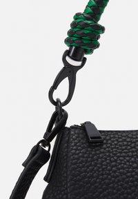 Sort struktureret læderhåndtaske med detaljer såsom et grønt og sort flet håndtag, metalclips og en lynlås med logo.