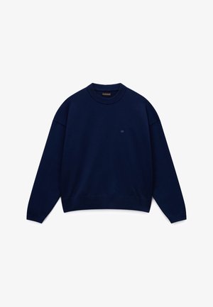 Donkerblauwe trui met ronde hals, lange mouwen en geribde boorden bij de manchetten, zoom en halslijn, met een klein geborduurd logo op de borst.