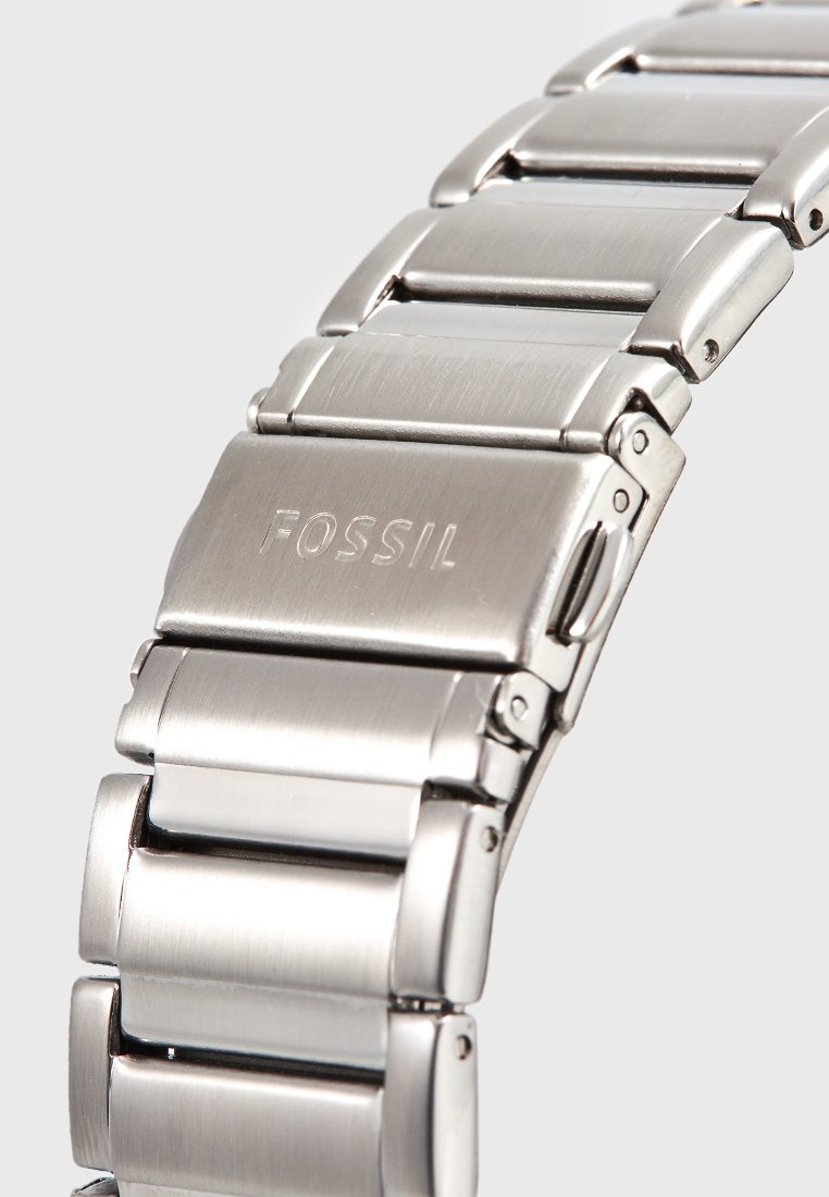 Silver metal watch bracelet with brushed and polished finishes, featuring rectangular links and a clasp with the "FOSSIL" logo engraved.