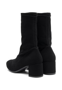 Botas de tobillo de ante negro con un diseño ajustado, tacón cuadrado y costuras visibles a lo largo de las costuras. Textura y forma general suave.