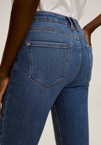 Blauwe denim jeans met een hoge taille, slim-fit ontwerp, licht vervaagde textuur en contrasterende stitching. Bevat twee achterzakken.