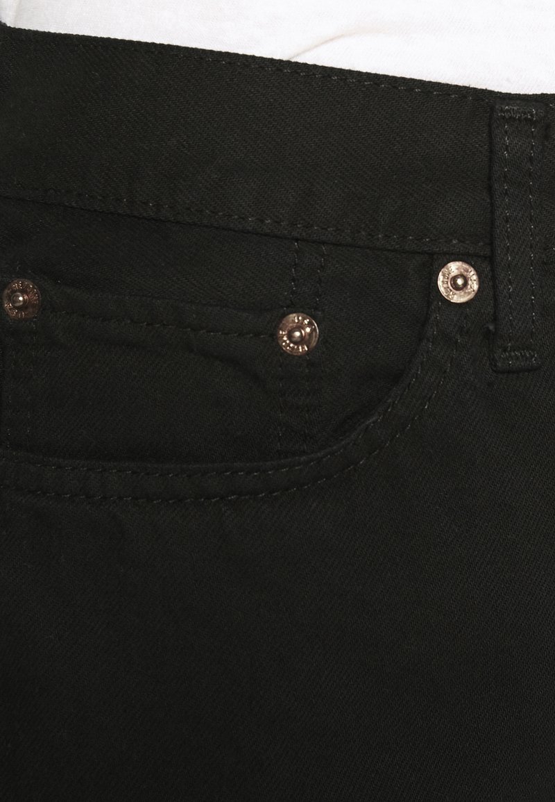 Schwarze Jeans mit subtiler Textur, Fünf-Taschen-Design und Hardware in Kupferoptik mit Stichdetails.