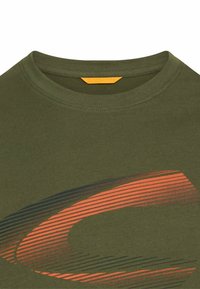 Oliven grønt t-shirt med rund halsudskæring, der har et abstrakt sort og orange stribet design. Indeholder et lille orange mærkat ved halsen.