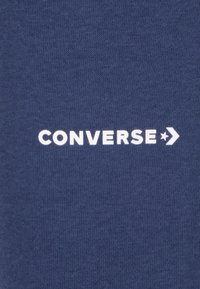 Navy cotton fabric featuring the white text "CONVERSE" and a star logo, with a smooth texture and no additional patterns.