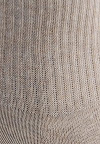 Chaussettes beige à côtes, fabriquées en matériau doux et extensible, avec une texture lisse et un motif de tricot uniforme.