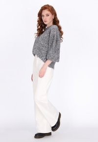 Grauer Strickpullover mit kurzen Ärmeln, lockerer Schnitt, kombiniert mit weißen Weitgeschnittenen Hosen und schwarzen Plateau-Schuhen, glatte Textur und klare Linien.