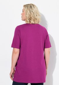 T-shirt viola a maniche corte con una vestibilità rilassata, texture morbida e scollo rotondo. Il retro presenta una finitura liscia senza motivi visibili.