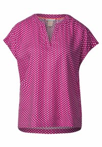 Kortärmad, magenta blus med V-ringning och ett geometriskt vitt mönster över hela plagget. Lätt tyg med en avslappnad passform och sidoslitsar.