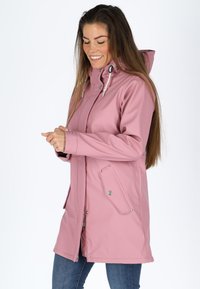 Giacca impermeabile rosa con cappuccio, dotata di bottoni a pressione, tasche laterali e un design elegante. Il tessuto ha una texture liscia.